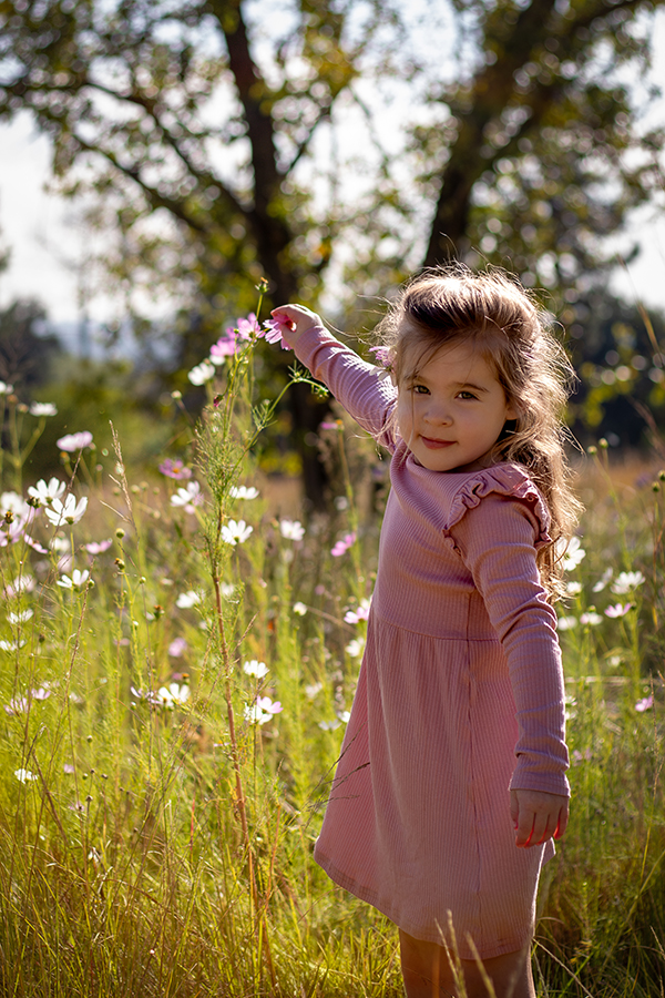 girl in pink dress picking flowers